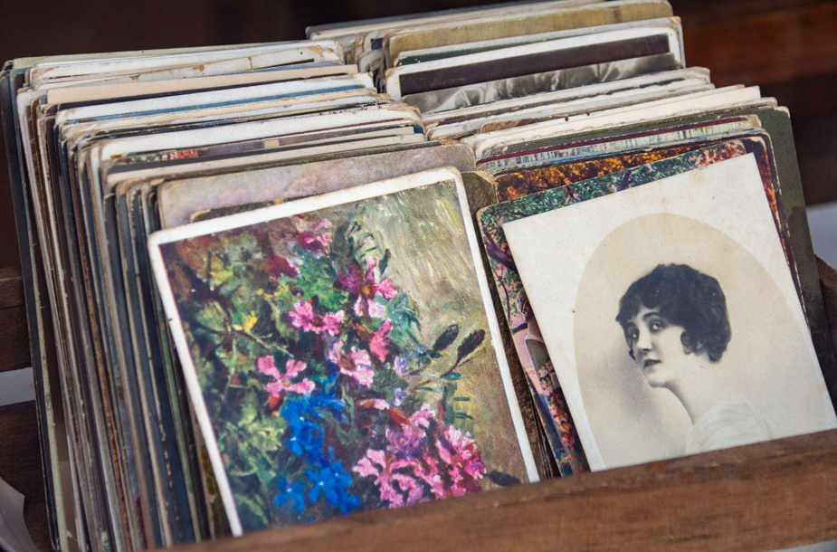 a collection of vintage postcards in a wooden box featuring floral art and a sepia portrait